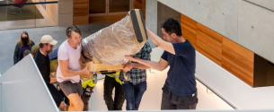 A wrapped work of art being carried up the stairs of the museum